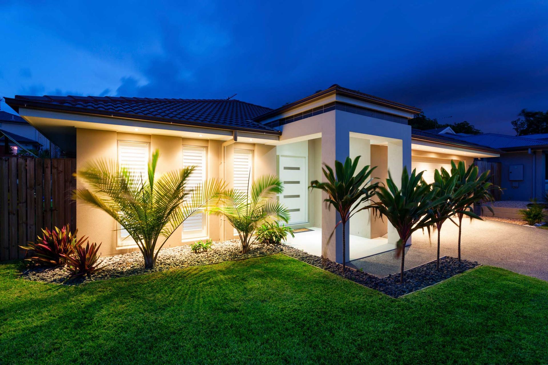 A House Is Lit Up At Dusk With Palm Trees In Front Of It – Sydney, NSW - Dallimont Electrical