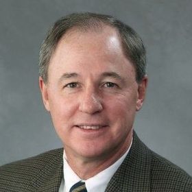 A man in a suit and tie is smiling for the camera.