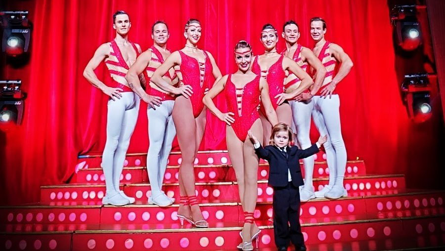 A group of dancers are posing for a picture on a stage.