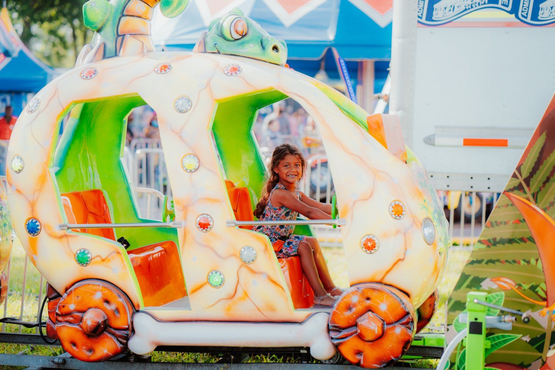A little girl is riding a roller coaster at an amusement park.