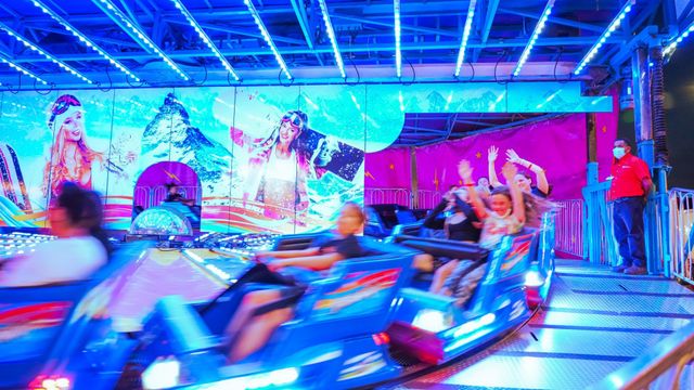 A group of people are riding a roller coaster at an amusement park.