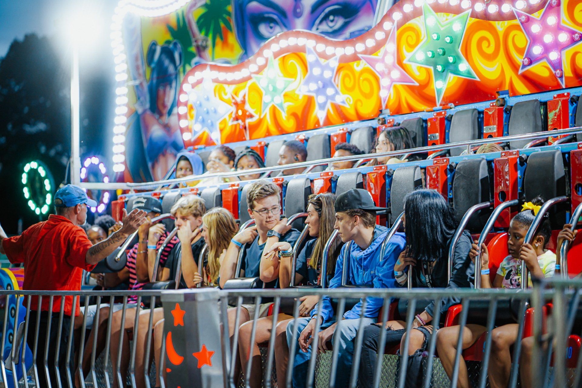 A group of people are riding a roller coaster at a carnival.