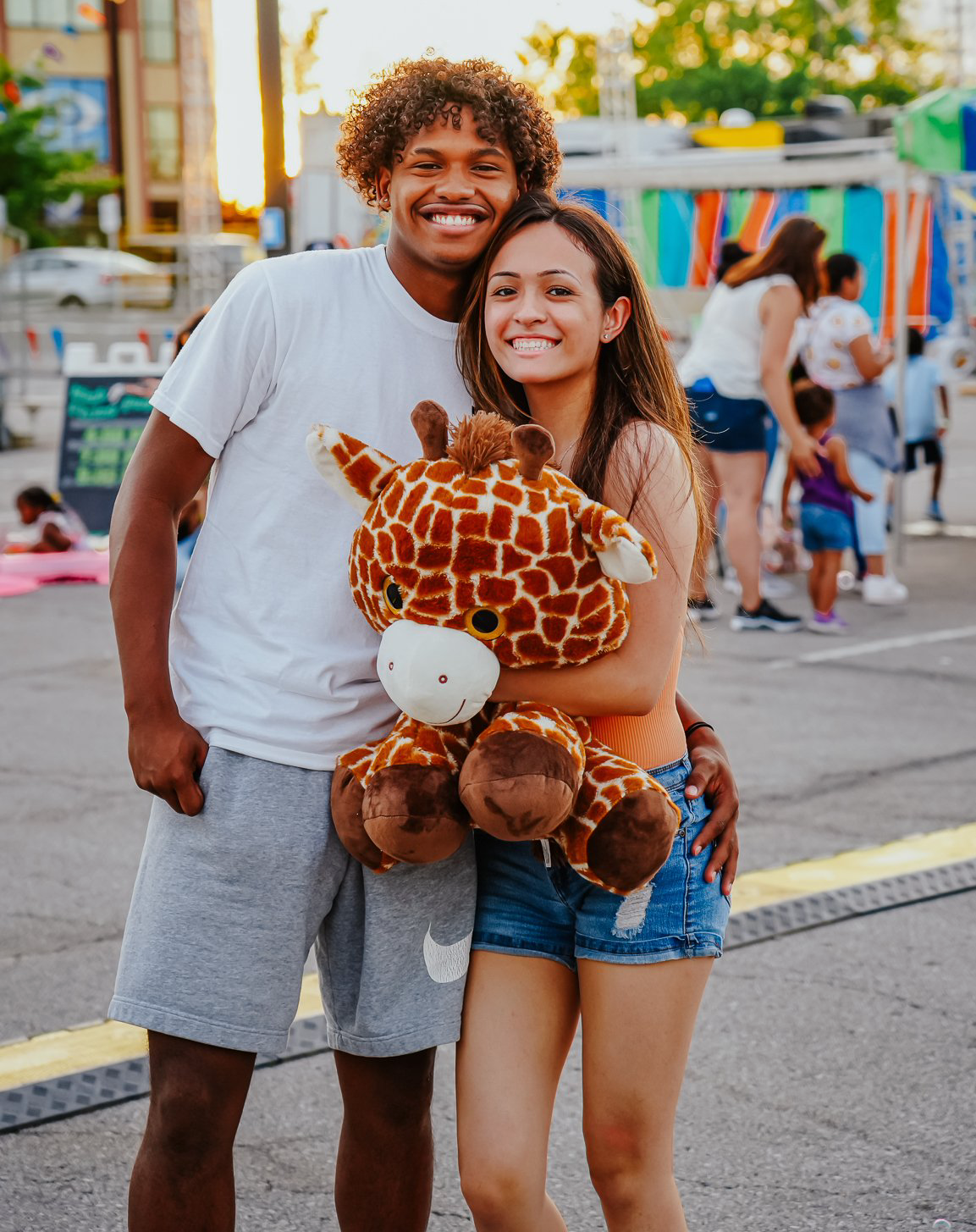 A man and a woman are standing next to each other holding a stuffed giraffe.