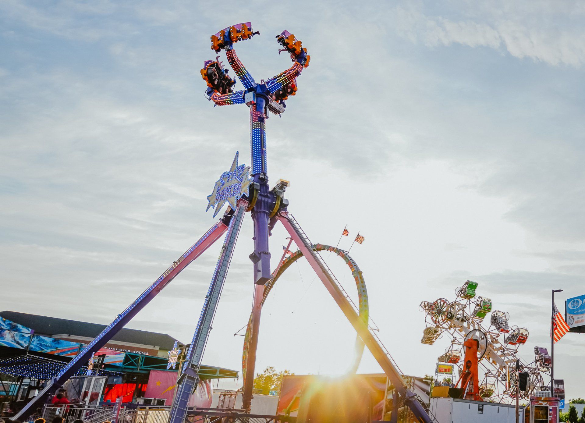 A roller coaster at an amusement park with the sun shining through the clouds.
