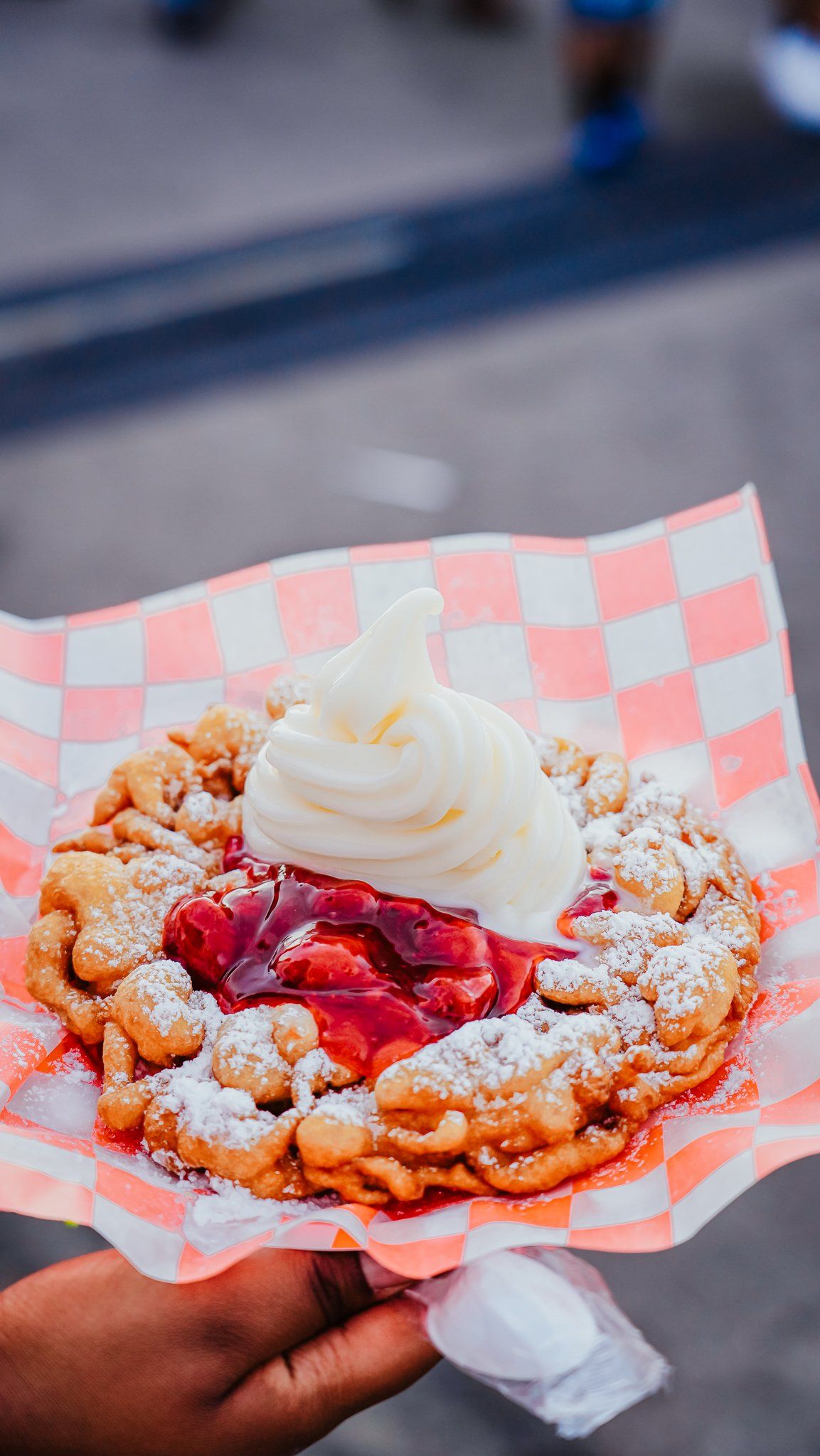 A person is holding a waffle with ice cream and strawberry sauce.