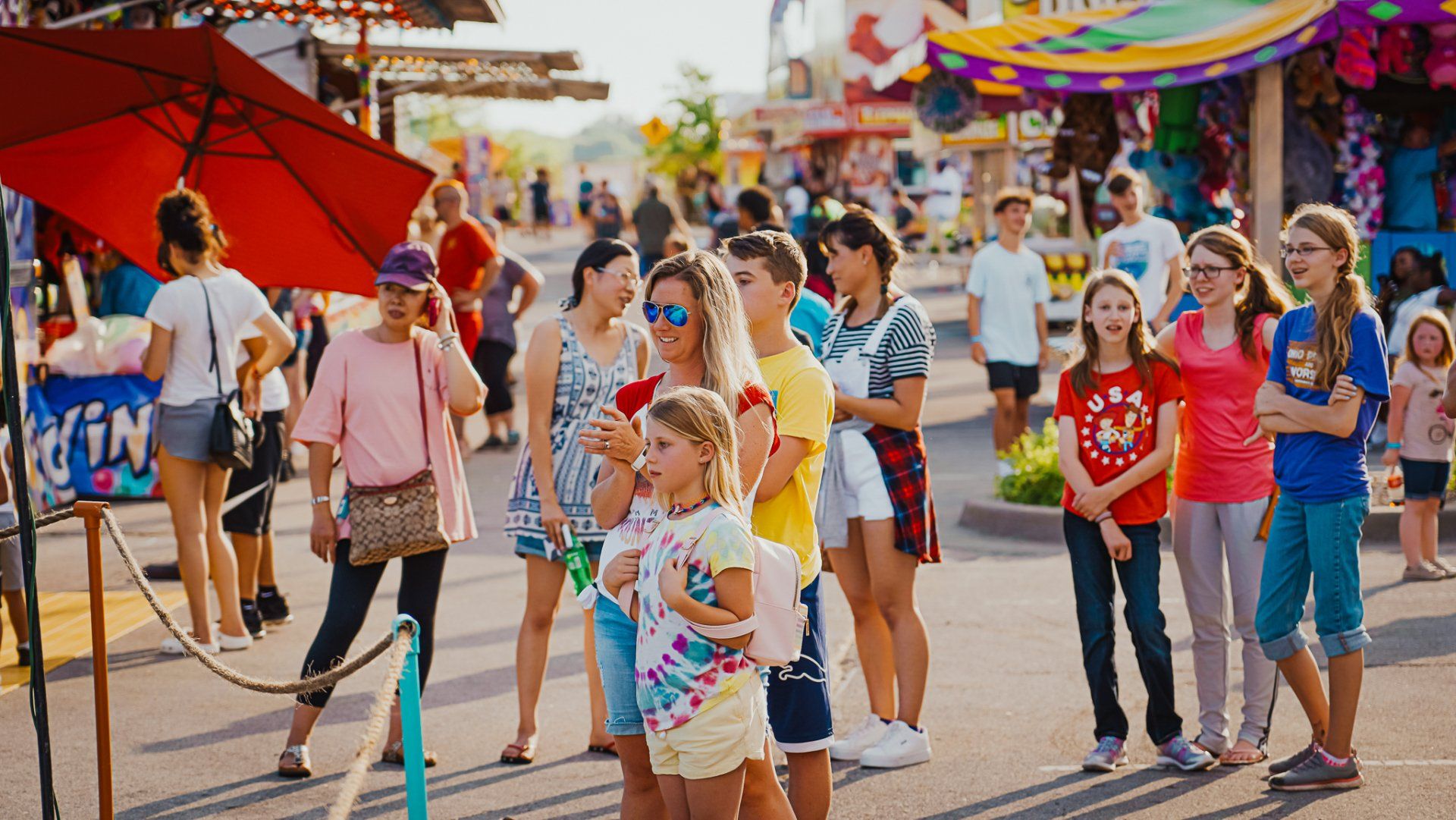 A group of people are standing in a line at a carnival.