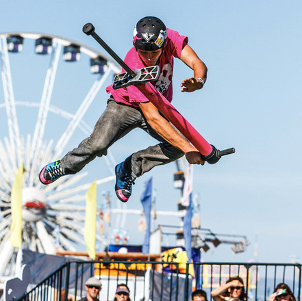 A man is jumping in the air with a ferris wheel in the background