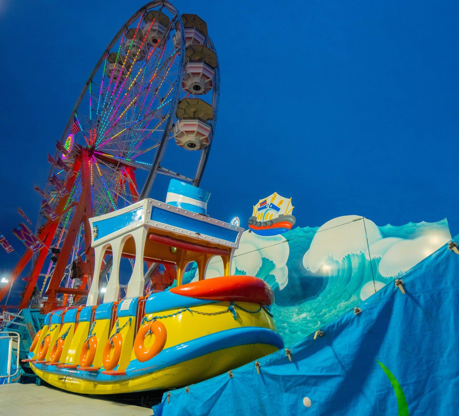 A carnival ride with a ferris wheel in the background