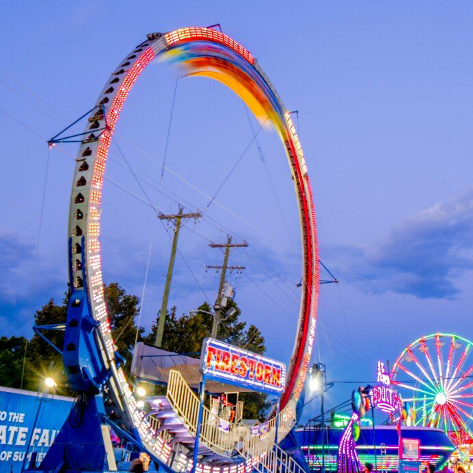 A ferris wheel at a carnival with a sign that says state fair