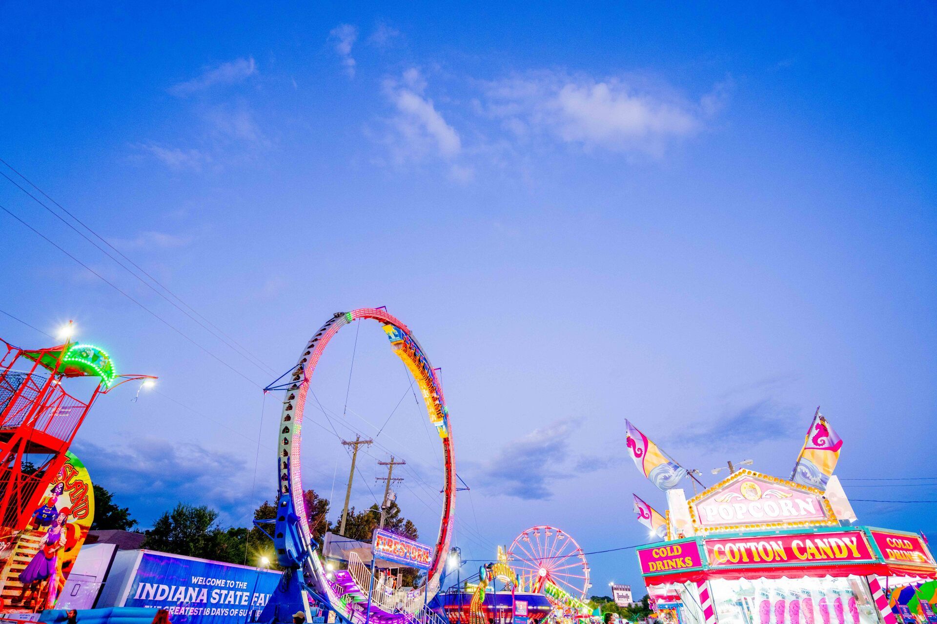A carnival with rides and a ferris wheel at night.