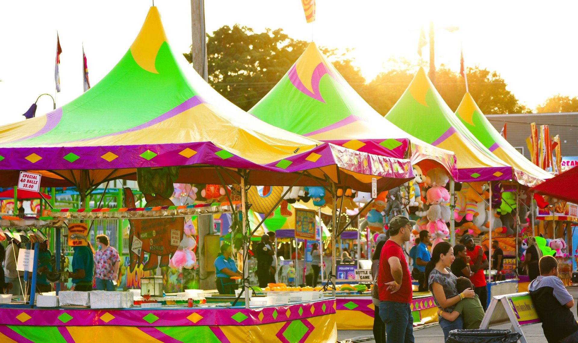 A group of people are standing in front of colorful tents at a carnival.