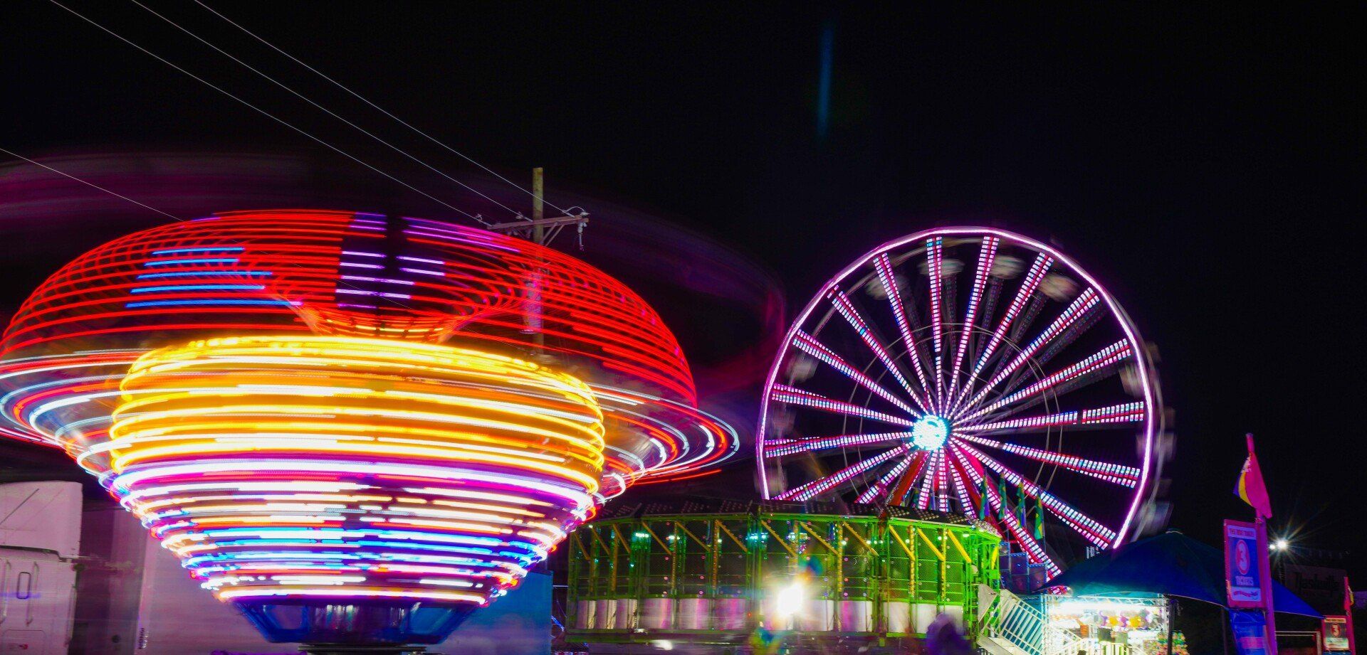 A carnival at night with a ferris wheel and a ufo.