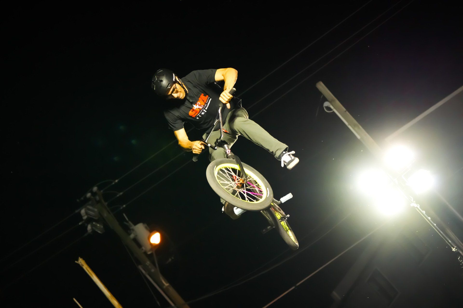 A man is doing a trick on a bike at night