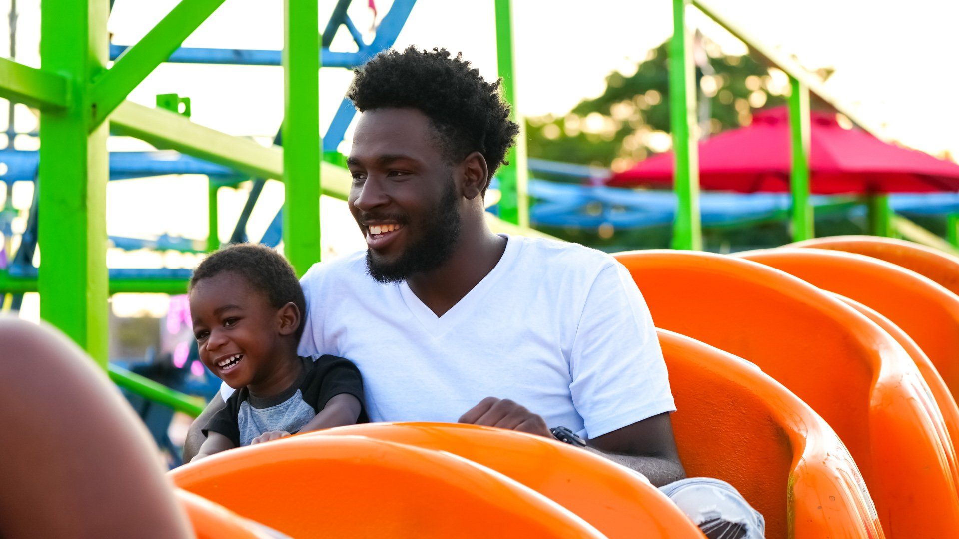 A man and a child are riding a roller coaster at an amusement park.