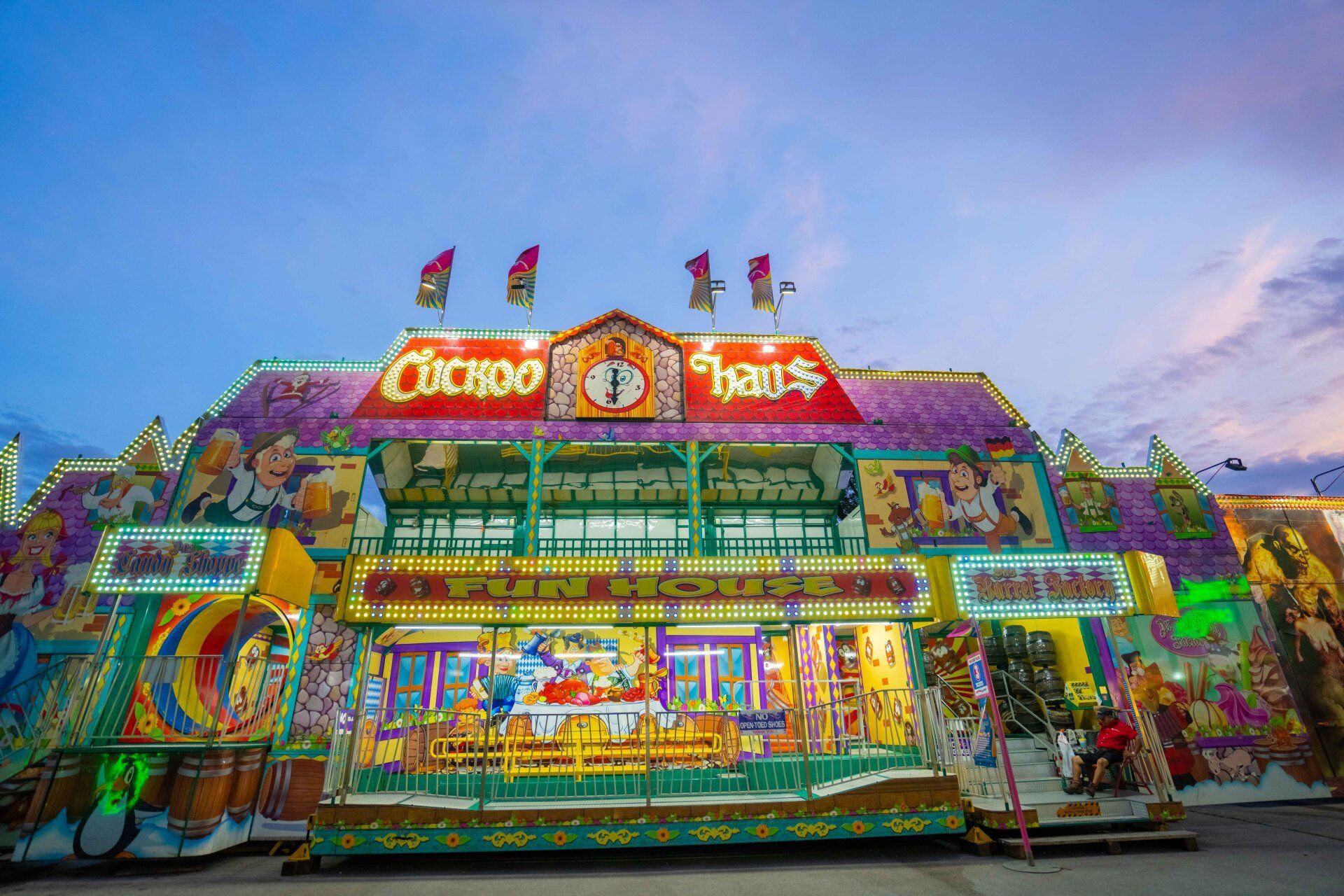A carnival ride is sitting in front of a building with a blue sky in the background.