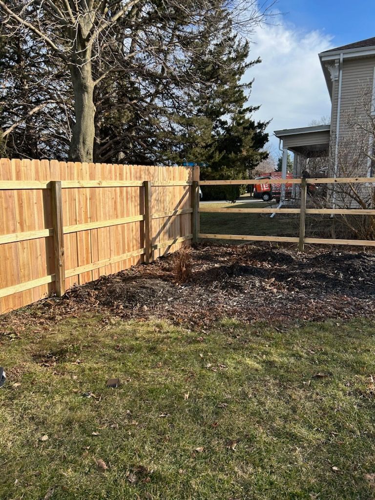 A wooden fence is in the backyard of a house.