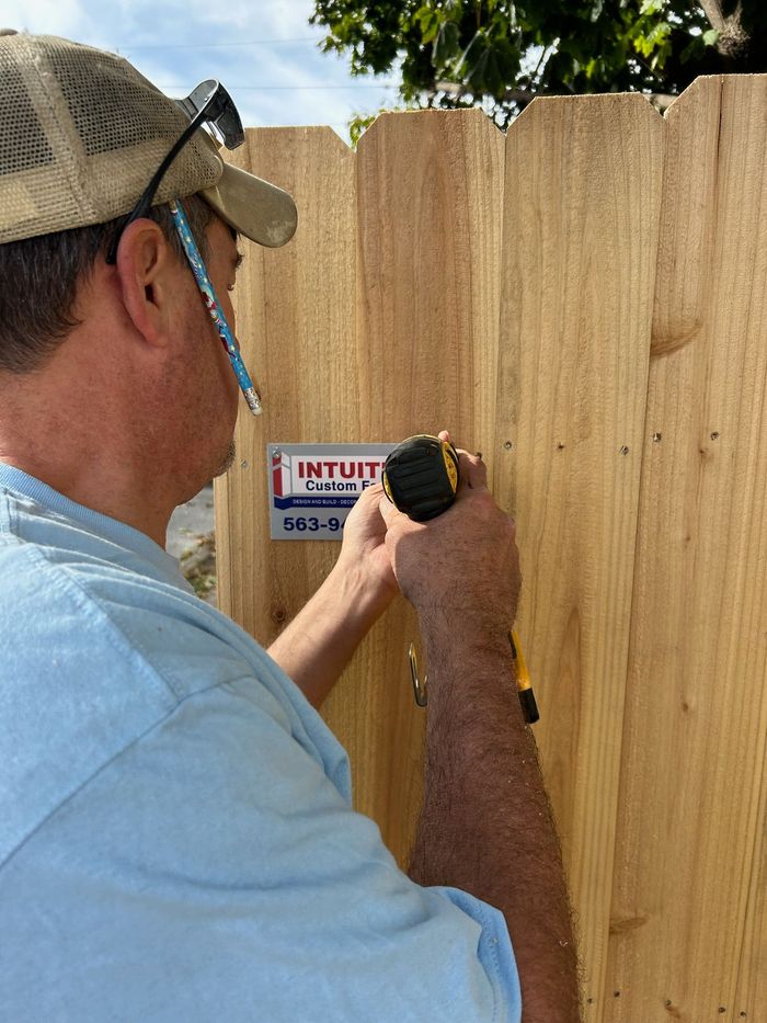 A wooden fence with a sign that says intuition custom fences