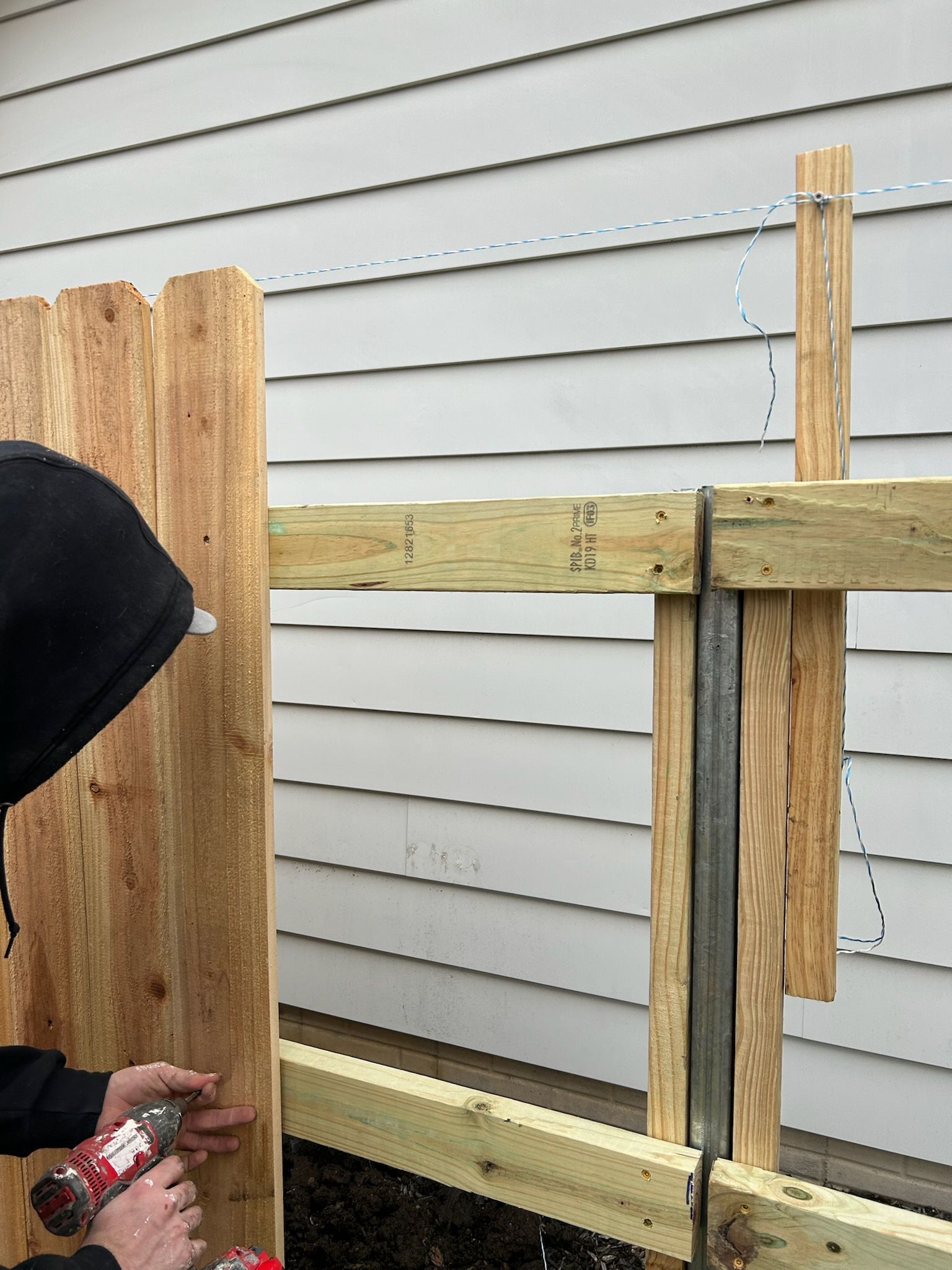 A person is working on a wooden fence in front of a house.