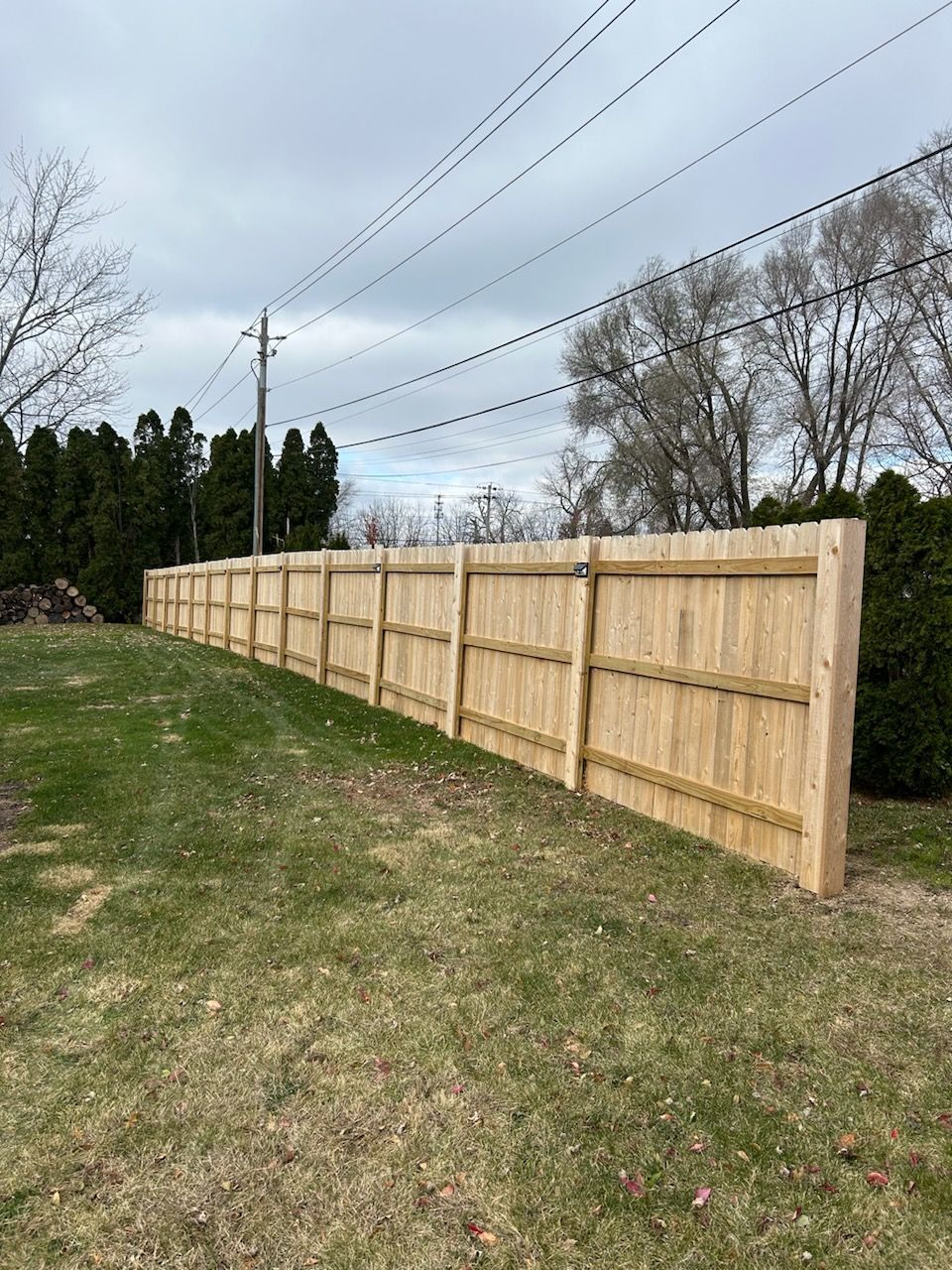 A long wooden fence is sitting in the middle of a grassy field.