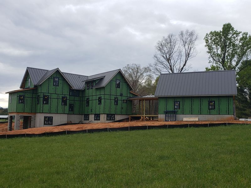 Green house under construction on a grassy lot under a cloudy sky