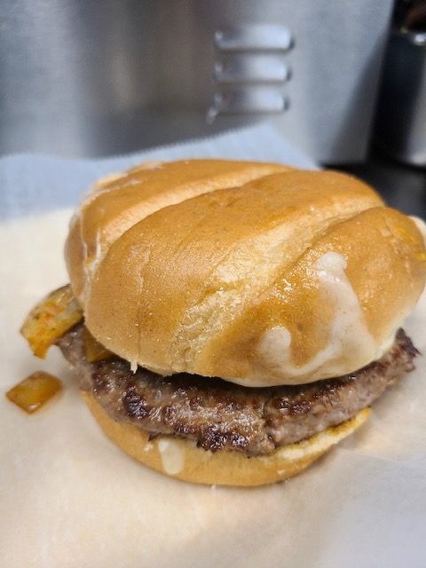 Hamburger on a bun with a grilled patty and melted cheese, on a white paper.