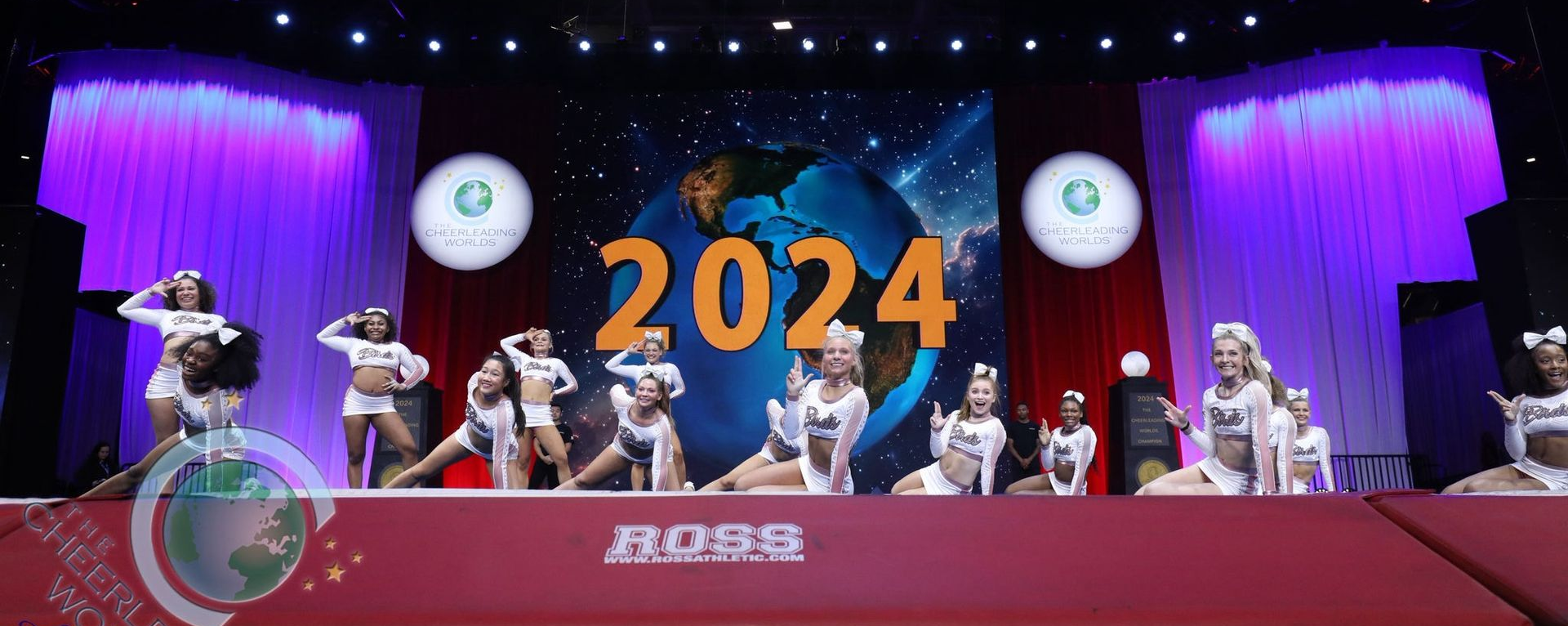 A cheerleading team performs on a stage decorated with a large 