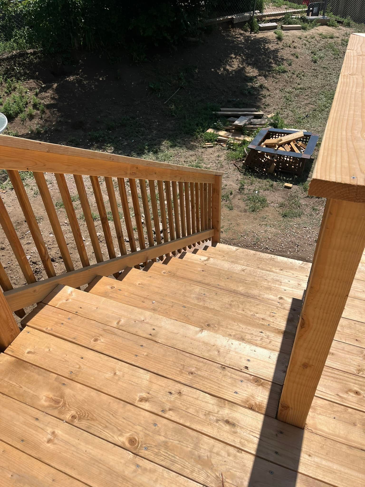 Wooden outdoor stairs leading down from a deck, with a railing on the left.