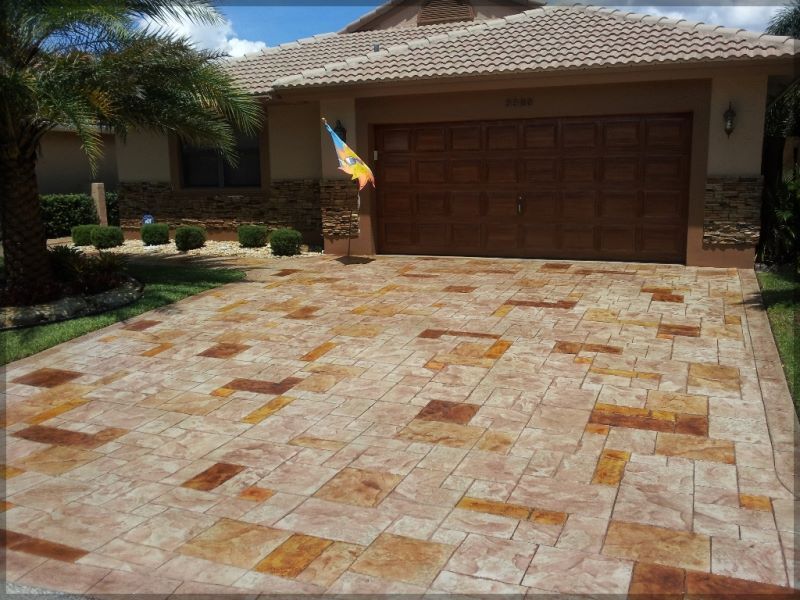 Driveway with decorative stone pattern leading to a house with a brown garage door.