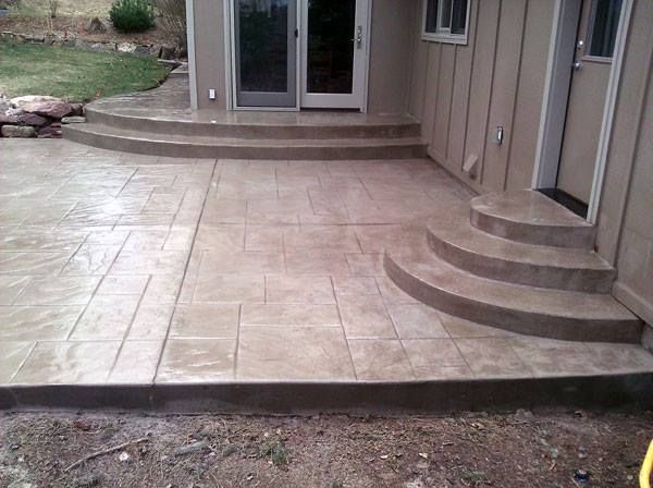 Stamped concrete patio with steps leading to doors and a side entrance, colored tan.