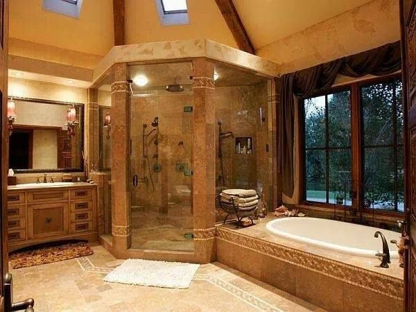 Luxurious bathroom with large glass shower, tub, and wooden vanity. Earth-toned decor and a window with a view.