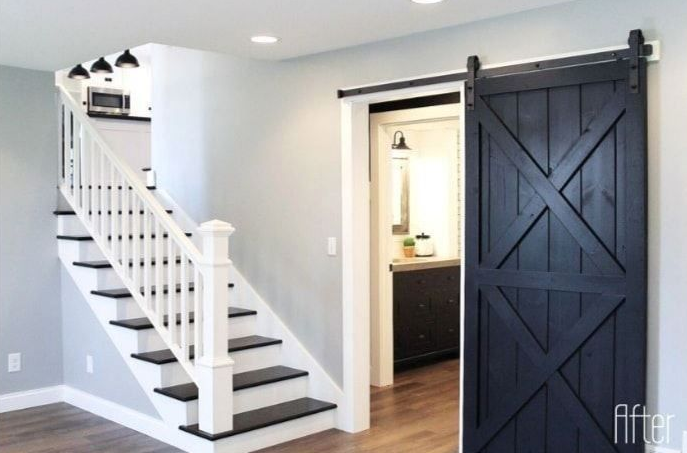 Interior with black sliding barn door, white staircase, and grey walls.