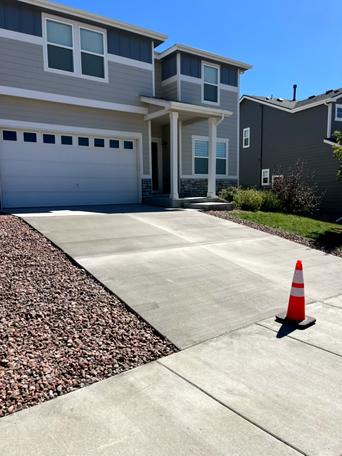 Residential home with driveway, a traffic cone, and sidewalk.