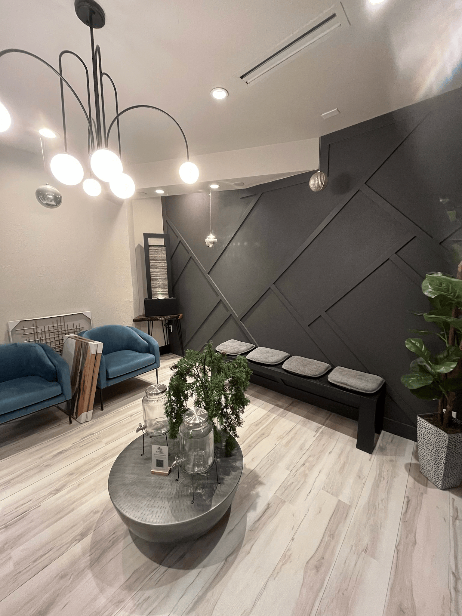 Modern waiting room with blue chairs, gray bench, and decorative black wall.