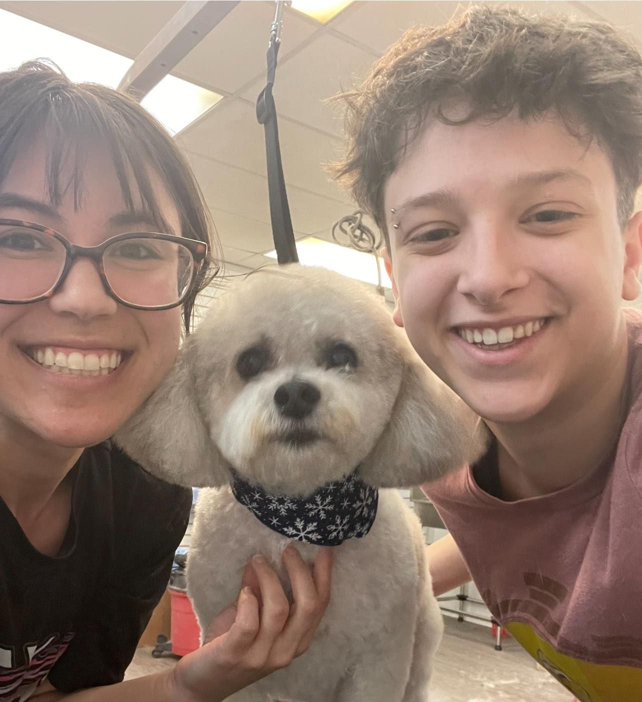 A man and a woman are posing for a picture with a small white dog.