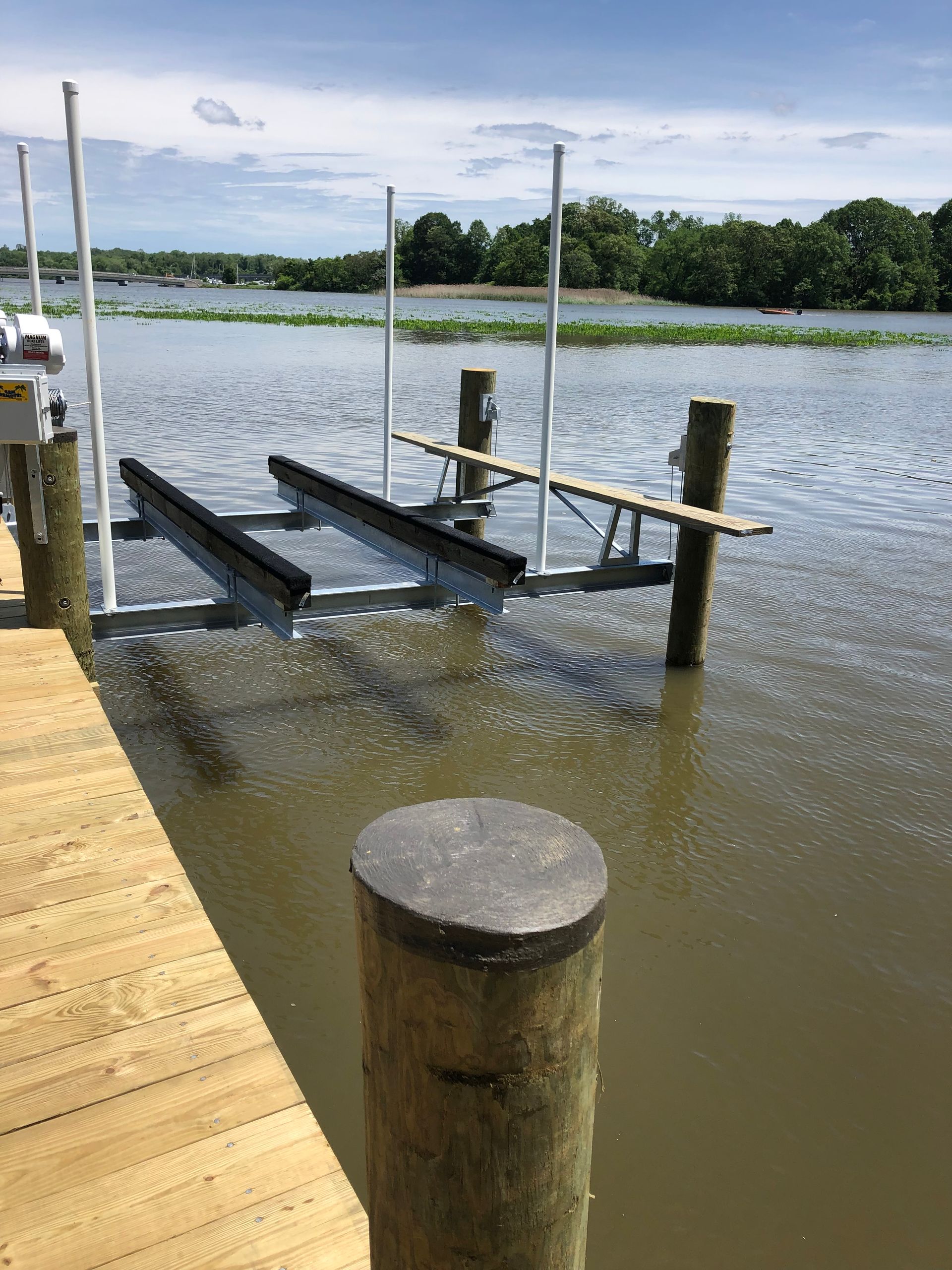 A boat lift is attached to a wooden dock in the water.
