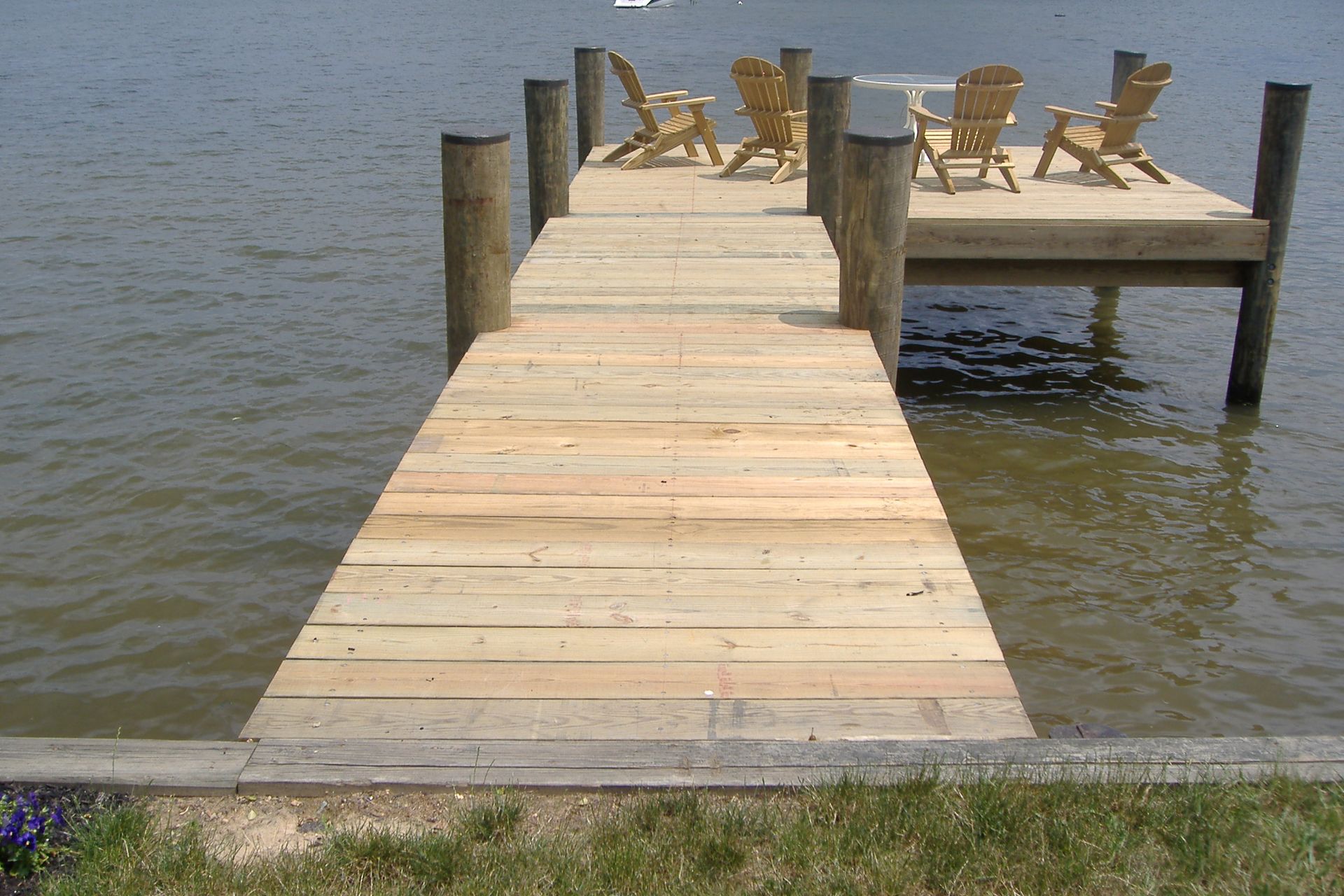 A wooden dock with chairs on it in the water
