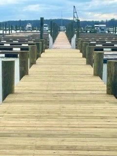 A long wooden dock leading to a marina filled with boats.