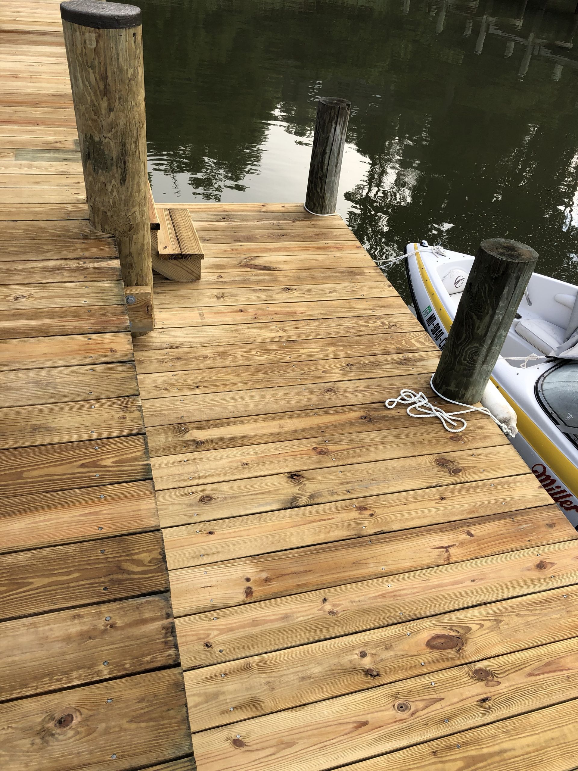 A wooden dock with two kayaks docked at the end of it.
