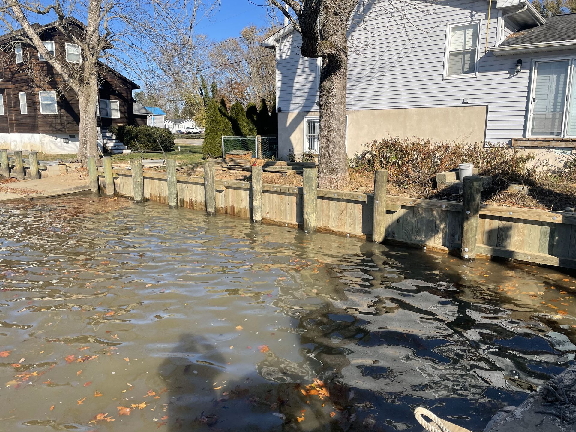 A flooded yard with a dock and a house in the background.