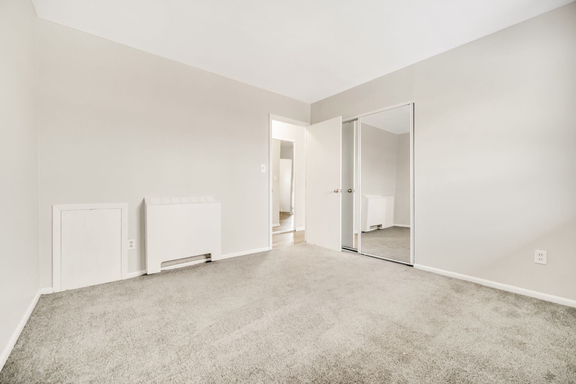 An empty bedroom with a carpeted floor and white walls.