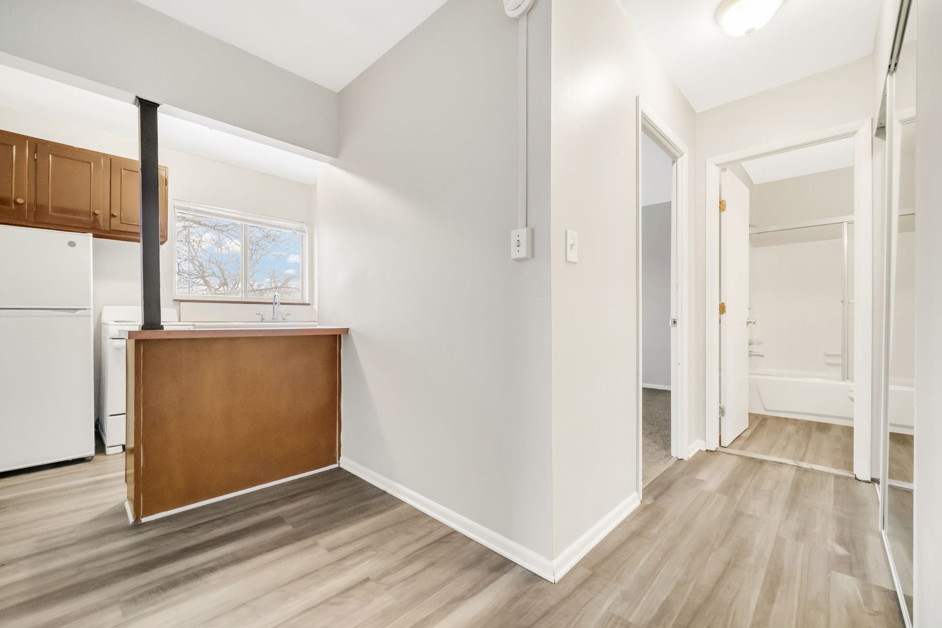 A hallway leading to a kitchen and a bathroom in a house.