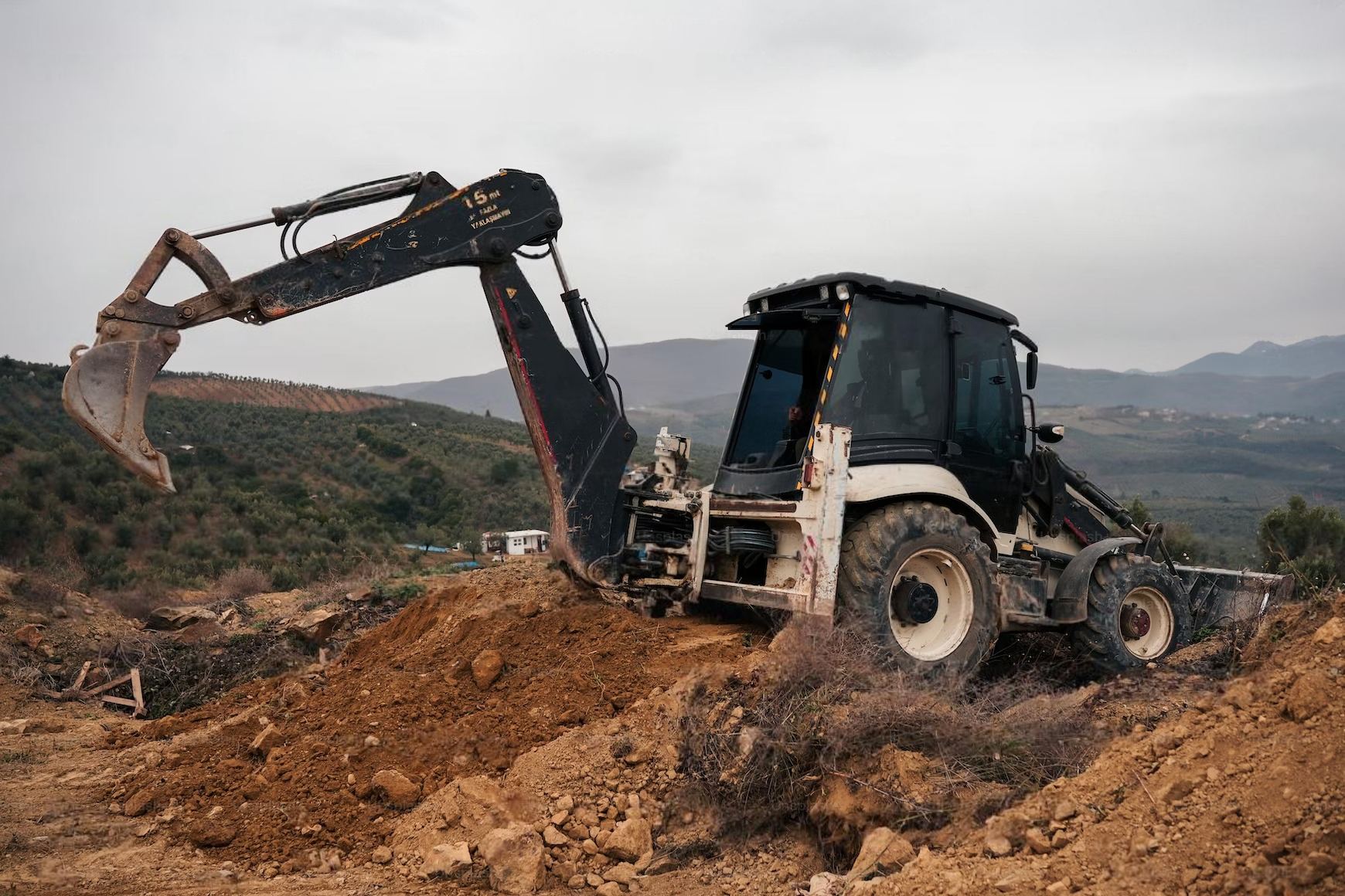 a bulldozer is digging a hole in the dirt in a field .