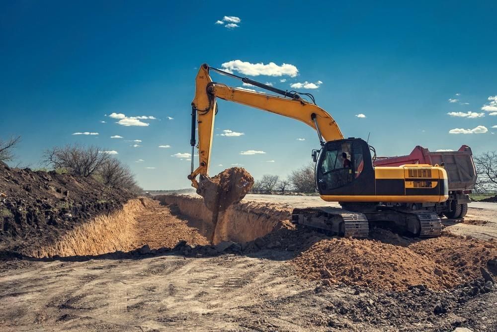 a yellow excavator is digging a hole in the dirt on a construction site .