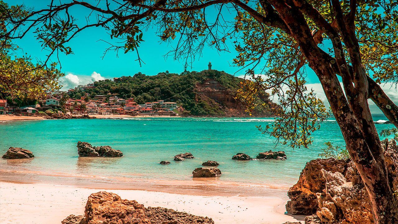 praia com pedras e ilha ao fundo em Morro de São Paulo