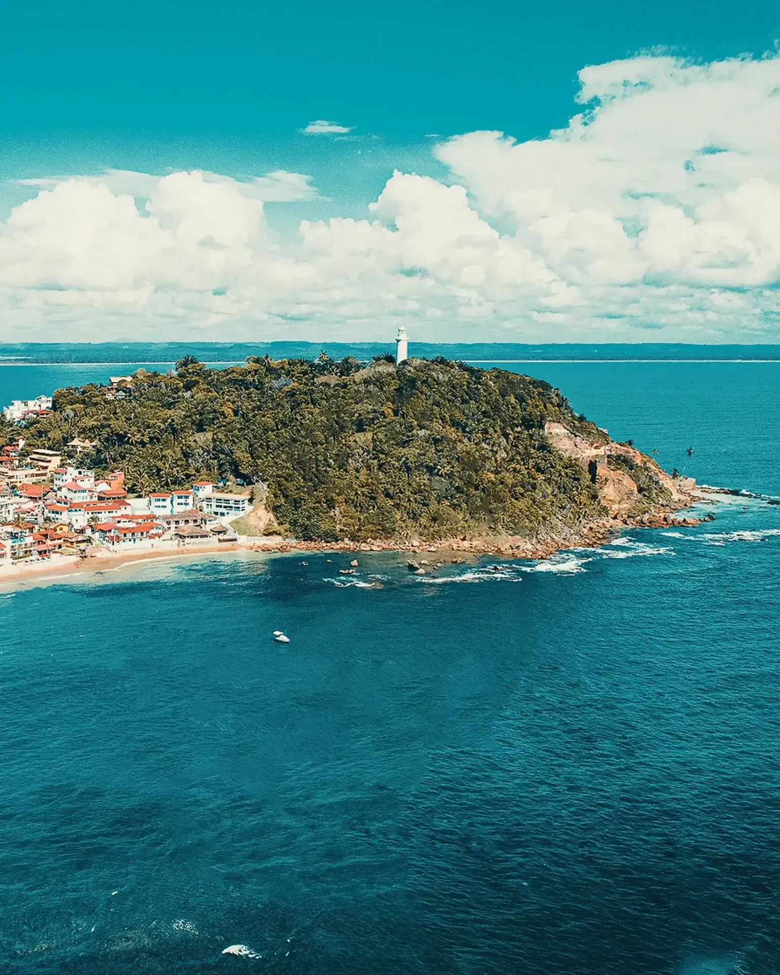 um farol fica no topo de uma colina com vista para o oceano