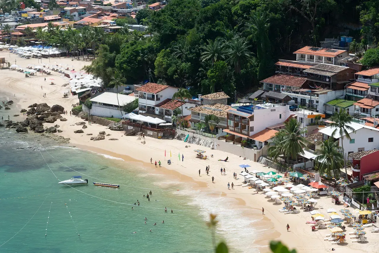 Imagem aérea da praia e de um vilarejo que fazem parte da história do Morro de São Paulo.