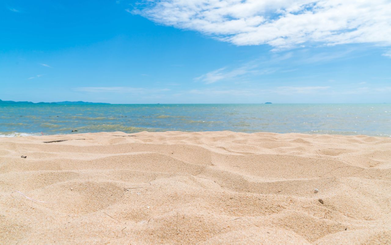 Imagem de uma praia deserta, com areia clara e mar verde, características da Praia de Pratigi