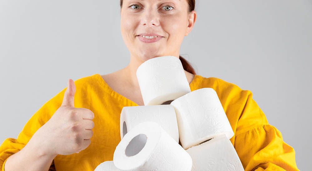 Verstopfung richtig erkennen. Frau in gelben Pullover hält Toiletten-Papier