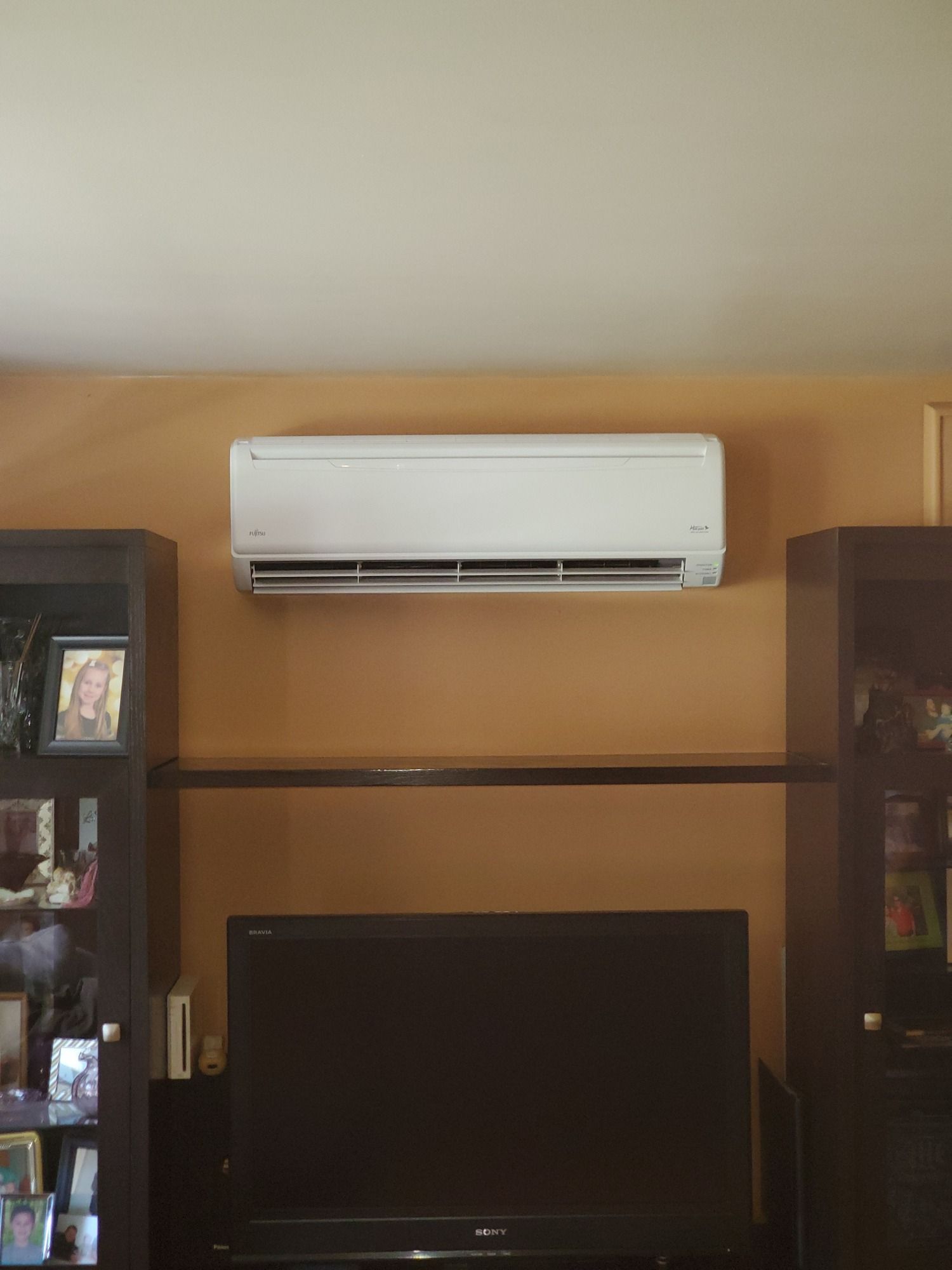 A living room with a flat screen tv and a wall mounted air conditioner.