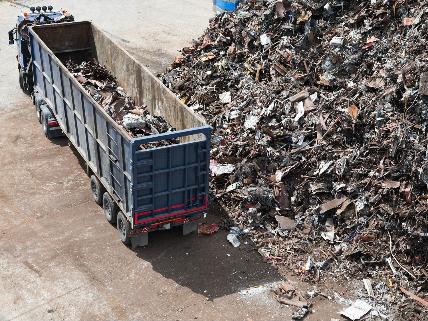 A dump truck is carrying a large pile of scrap metal.